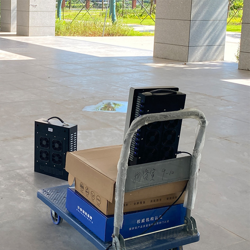 Handcart with boxes and portable mobile phone jammer in a courtyard